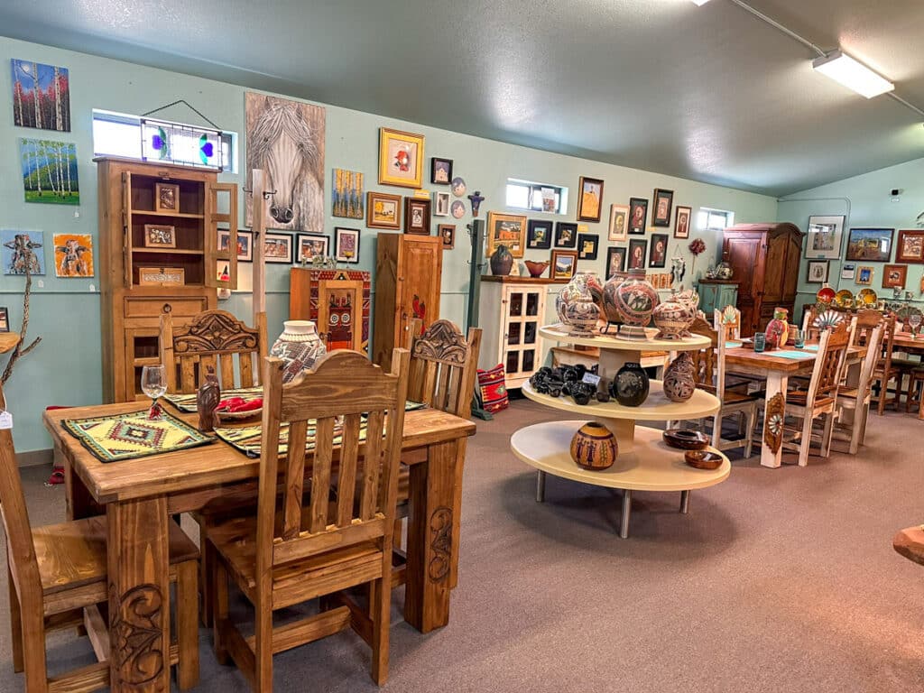 Cozy Southwestern art gallery interior filled with colorful artwork, traditional pottery, and rustic wooden furniture. The art totally makes New Mexico worth visiting